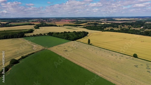 High angle drone shot over patchwork English countryside on a sunny day. 4k