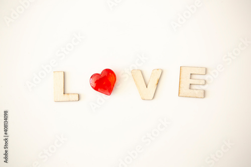 Wooden letters with the inscription of the word "Love" on a white background and next to a small red heart