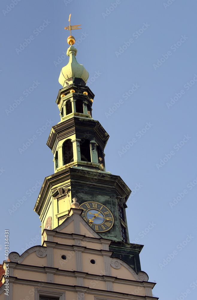 Rathausturm mit Uhr und goldener Wetterfahne vor strahlend blauem Himmel