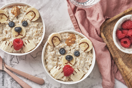 Oatmeal porridge bear with banana and berries, fun food art idea for kids food top view