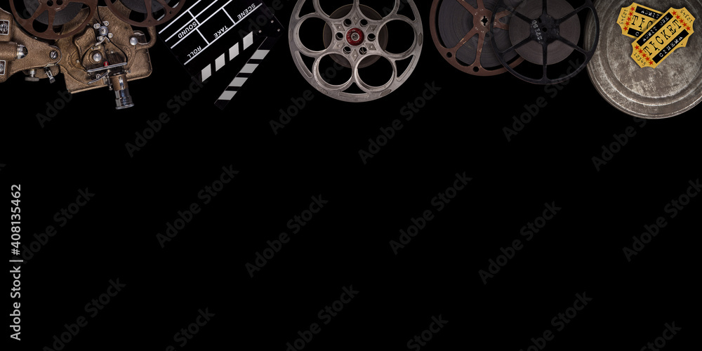 Cinema concept of vintage film reels, clapperboard and other tools on black background.