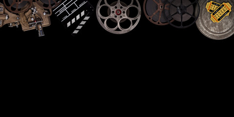 Cinema concept of vintage film reels, clapperboard and other tools on black background.