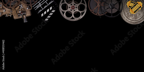 Cinema concept of vintage film reels, clapperboard and other tools on black background.