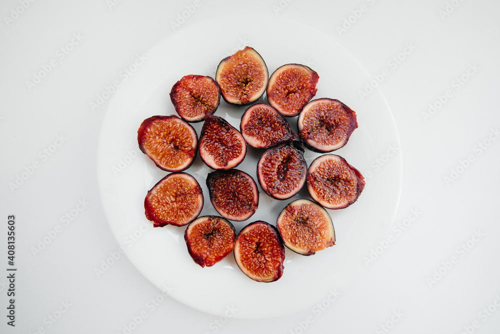Ripe and sweet figs cut and arranged in a plate on a white background with free space. Fruits and vegetarianism Ripe and sweet figs cut and arranged in a plate on a white background with free space. Fruits and vegetarianism