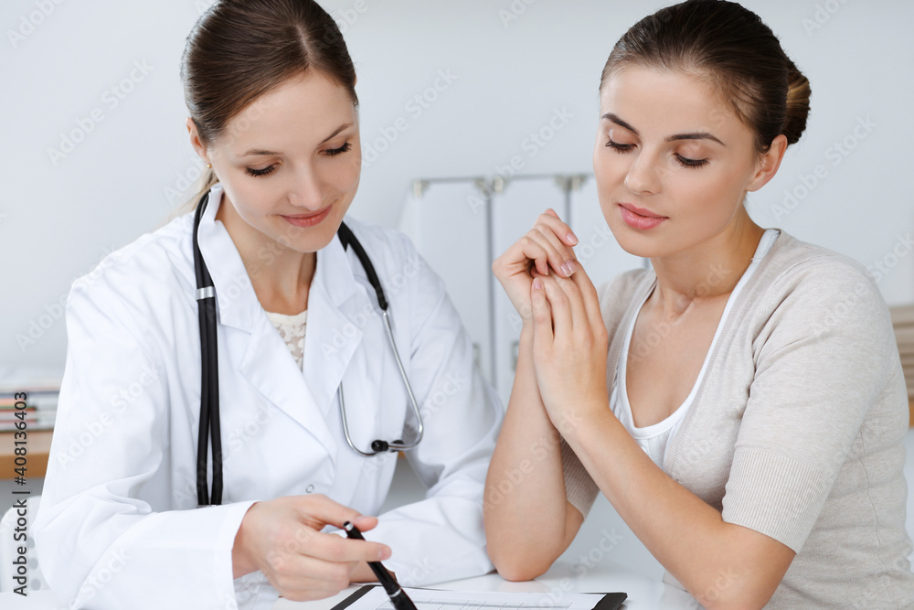 Doctor and patient are sitting and discussing health examination results in clinic office. Health care, medicine and good news concepts Doctor and patient are sitting and discussing health examination results in clinic office. Health care, medicine and good news concepts