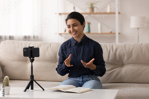 Foto Indian female popular video blogger shoot video content at home make topical review before webcam of phone fixed on tripod