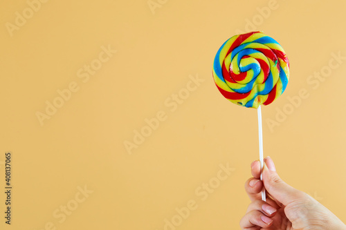 Hand holding colorful lollipops on orange background