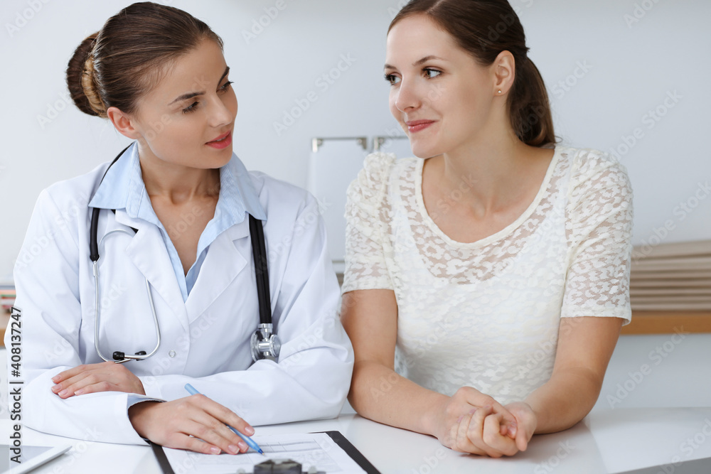 Doctor and patient sitting at the desk. The physician or therapist makes a diagnosis. Health care, medicine and patient service concept Doctor and patient sitting at the desk. The physician or therapist makes a diagnosis. Health care, medicine and patient service concept