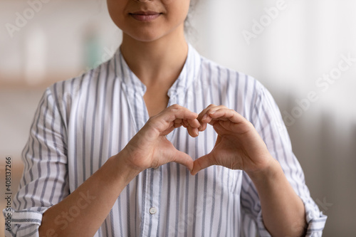 Cropped portrait of young female cardio patient expressing sincere gratitude appreciation to cardiologists volunteers charity givers. Close up of millennial woman posing to camera showing finger heart