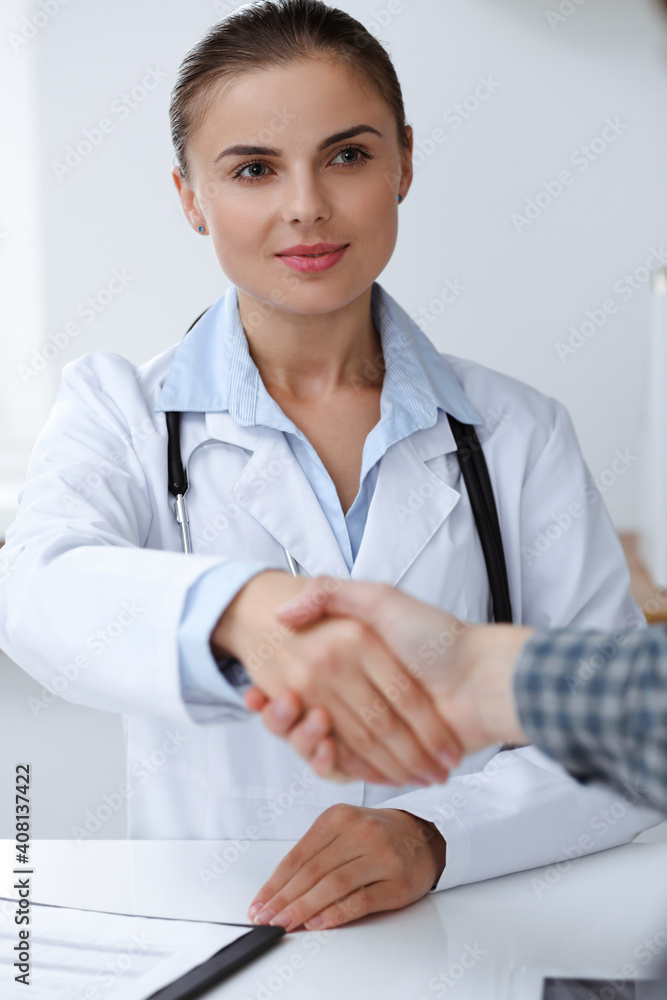 Woman-doctor smiling while shaking hands with her male patient. Medicine concept Woman-doctor smiling while shaking hands with her male patient. Medicine concept