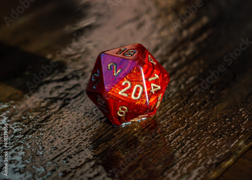 Marbled red 20 sided dice on a wet wooden surface