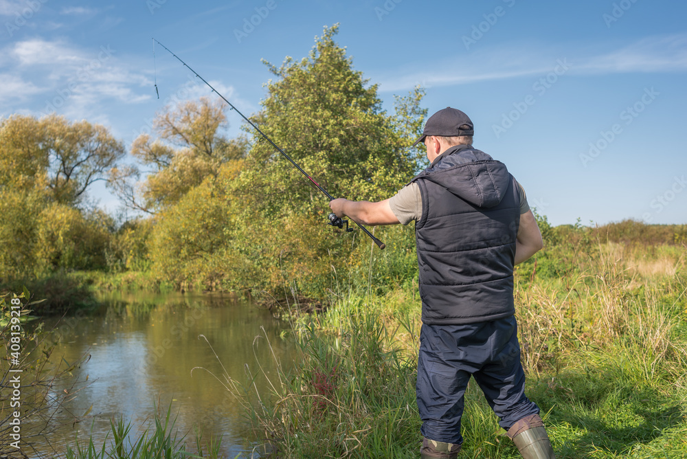 Man fishing with a rod on the river bank on a sunny day. Man fishing with a rod on the river bank on a sunny day.