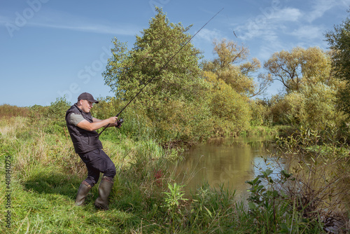 Man fishing with a rod on the river bank on a sunny day. © alexey351