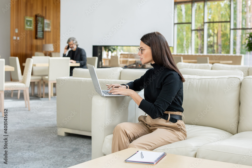 Serious young businesswoman analyzing online financial data in front of laptop Serious young businesswoman analyzing online financial data in front of laptop