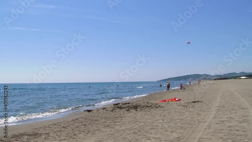 Ada Bojana sand beach with some people and kitesurfing. Small sea waves and bright blue sky. photo