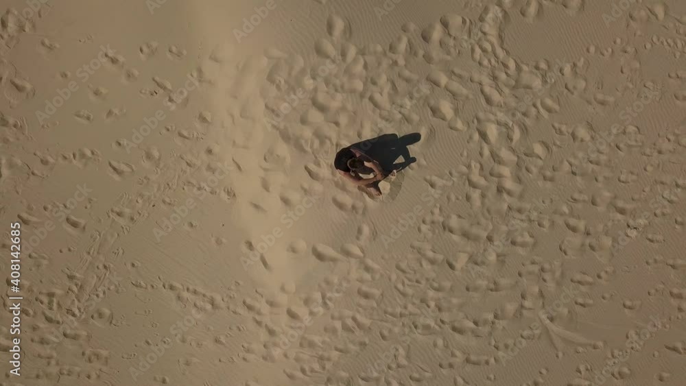 Spiral Aerial Zoom Out of Man Sitting on Sandy Desert Floor Joaquina Florianópolis (Drone - 4K) Spiral Aerial Zoom Out of Man Sitting on Sandy Desert Floor Joaquina Florianópolis (Drone - 4K)
