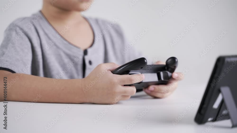 Asian boy about 5 years old using wheel controller for playing the racing video game Asian boy about 5 years old using wheel controller for playing the racing video game