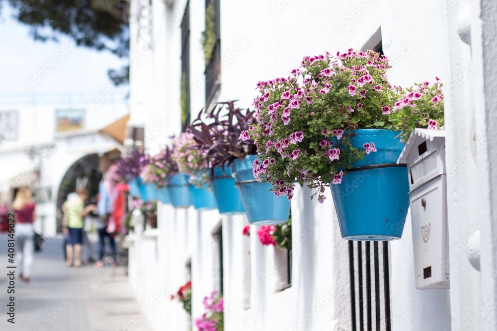 Blue flowerpots in a row on a white wall in an andalusian old town Mijas - obrazy, fototapety, plakaty 