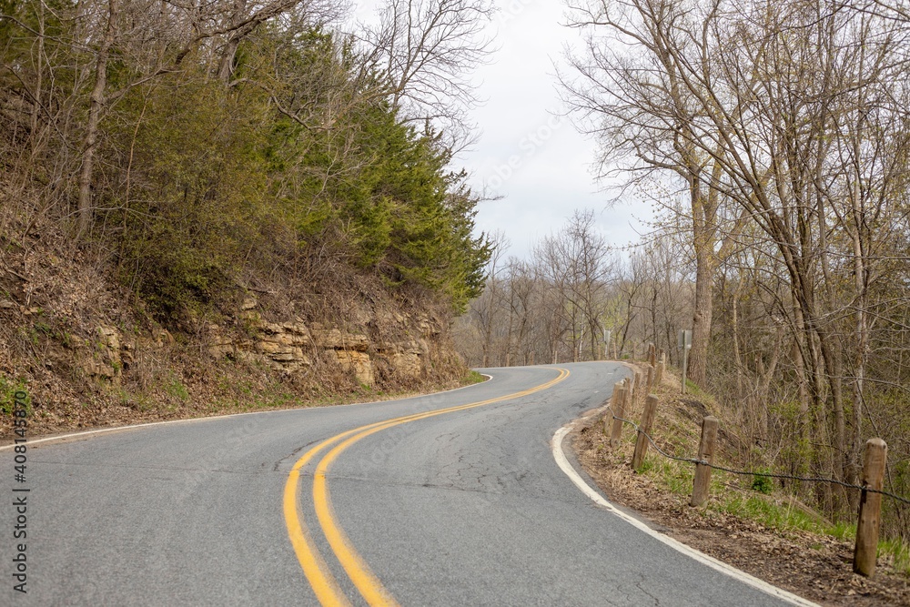 Fototapeta premium Wavy road in mountains between trees under sky