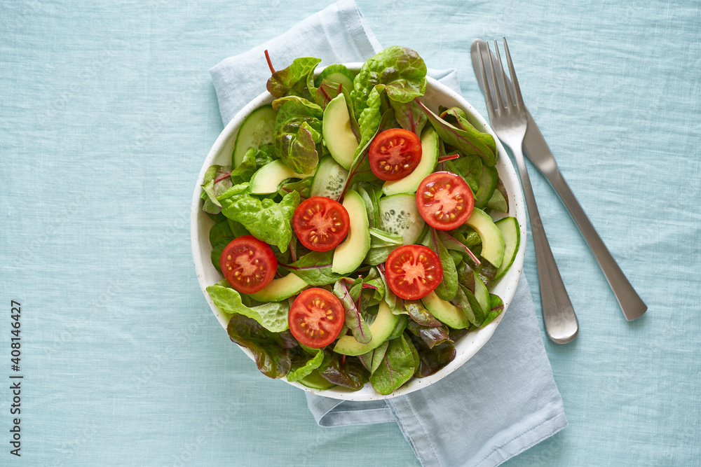 Vegan salad with tomatoes, cucumbers, avocado on pastel linen tablecloth. Vegeterian mediterranean food, low calories dieting meal Vegan salad with tomatoes, cucumbers, avocado on pastel linen tablecloth. Vegeterian mediterranean food, low calories dieting meal