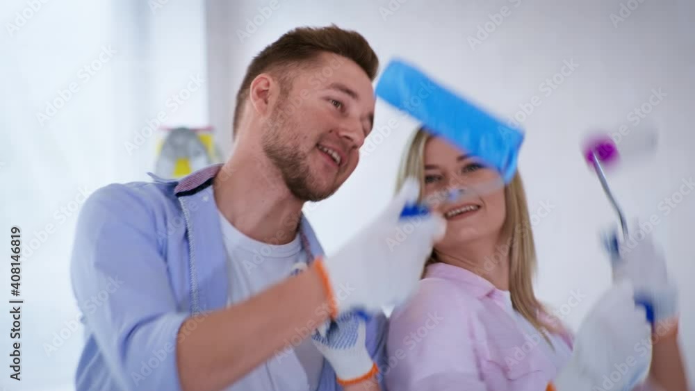 cheerful couple man and woman have fun dancing with rollers in their hands rejoice at repairs and painting walls in apartment cheerful couple man and woman have fun dancing with rollers in their hands rejoice at repairs and painting walls in apartment