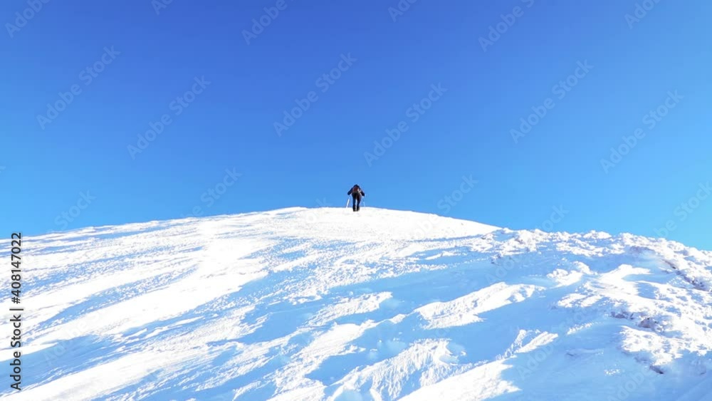 A hiker climbing mountain in winter season with snow and wind A hiker climbing mountain in winter season with snow and wind