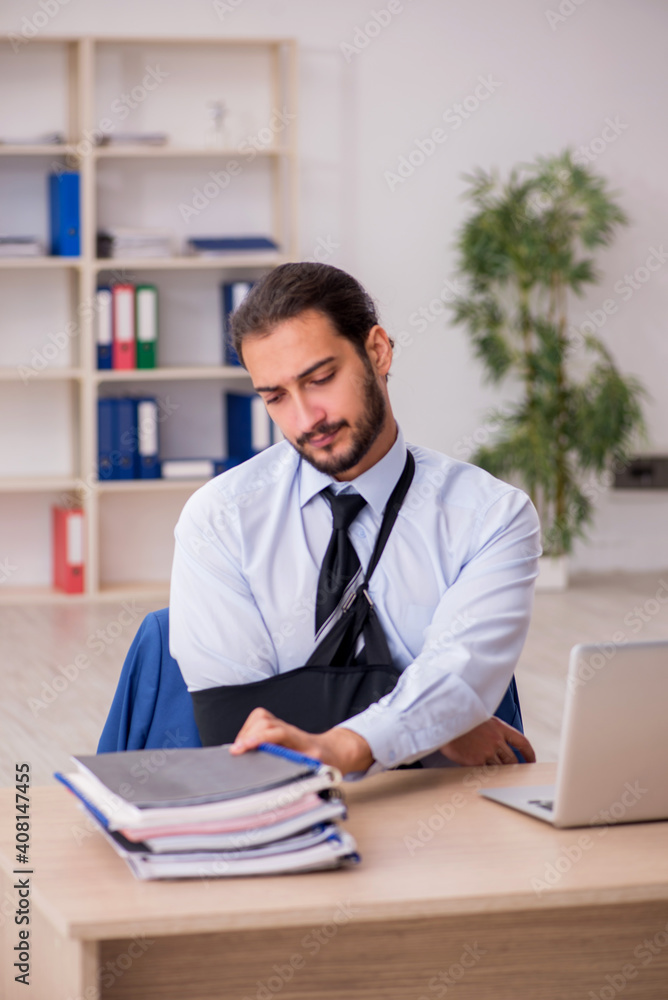 Young arm injured male employee working in the office Young arm injured male employee working in the office