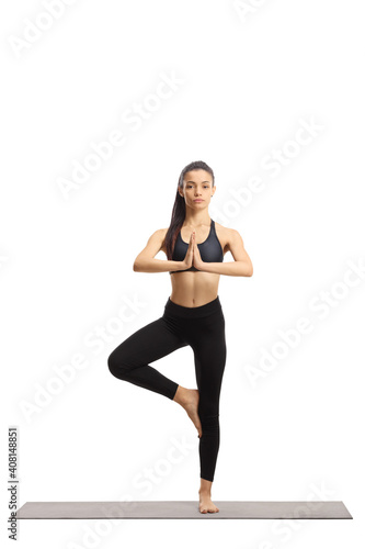 Full length portrait of a slim young woman exercising yoga on a mat