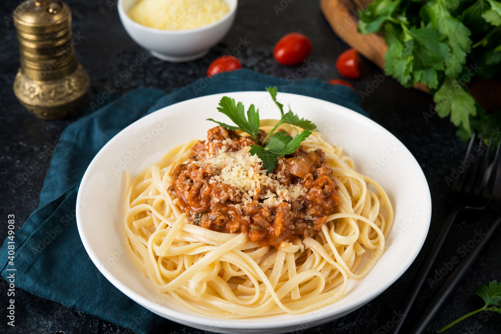 Italian pasta bolognese with greens on a black background