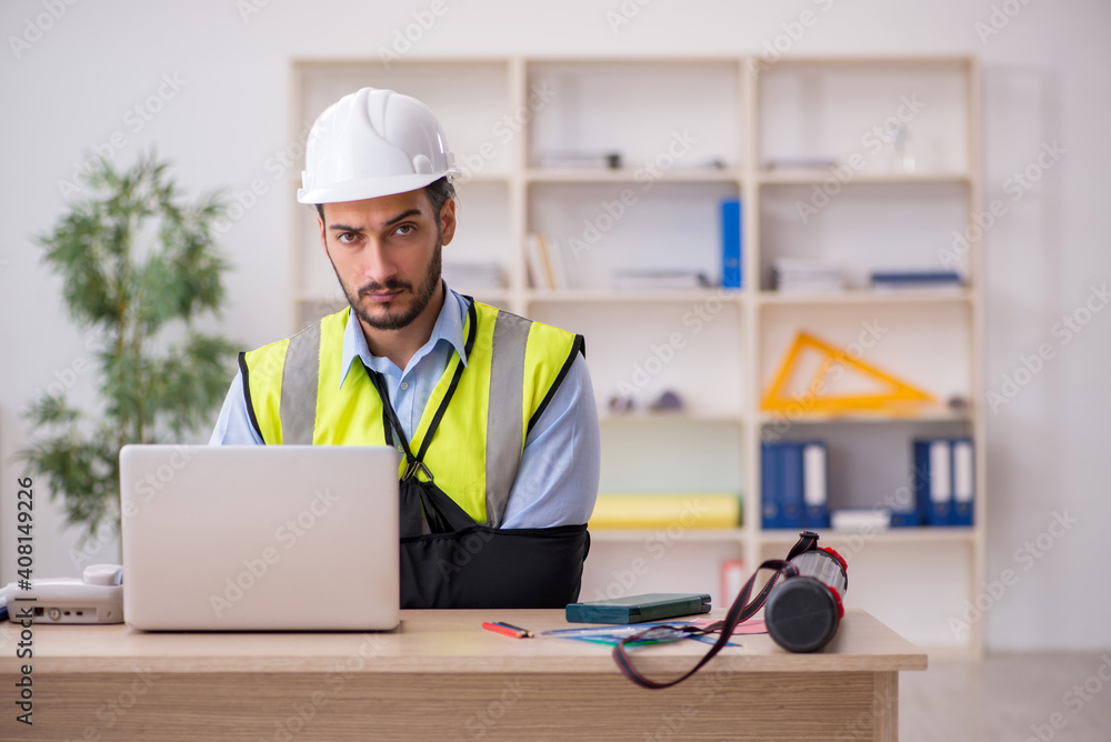 Young arm injured male architect working in the office Young arm injured male architect working in the office
