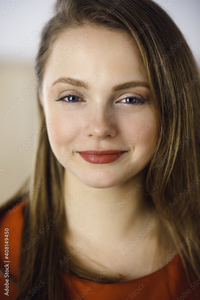 Head shot of a smart confident smiling millennial european woman standing with folded arms at home. Attractive young teenager student girl freelancer looking at camera, dressed in red Head shot of a smart confident smiling millennial european woman standing with folded arms at home. Attractive young teenager student girl freelancer looking at camera, dressed in red