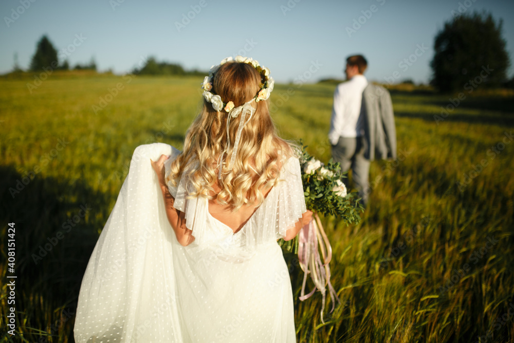 Back view of the groom and the bride in the field.