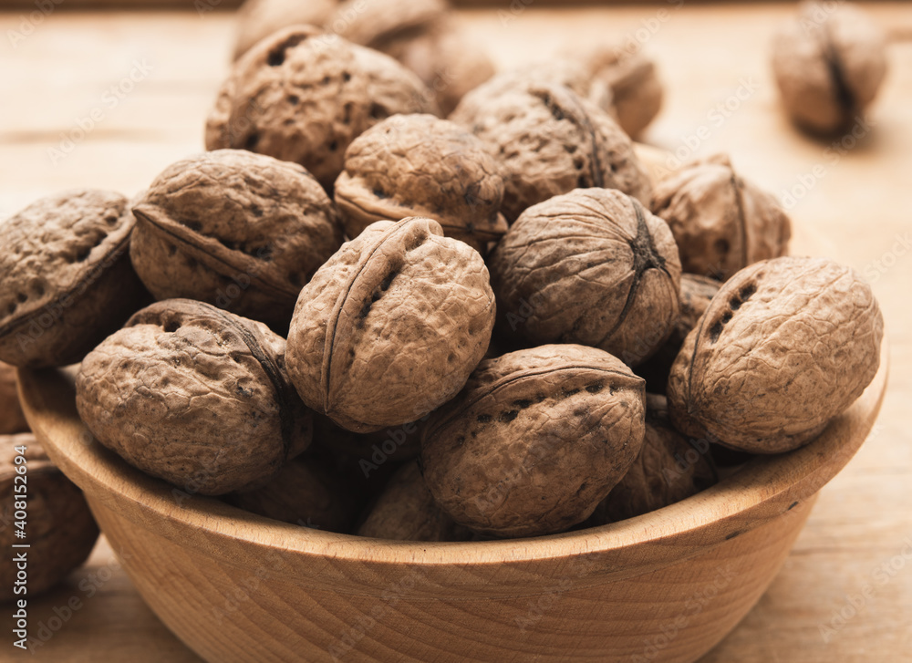 bunch of walnuts in a wooden plate on the table bunch of walnuts in a wooden plate on the table