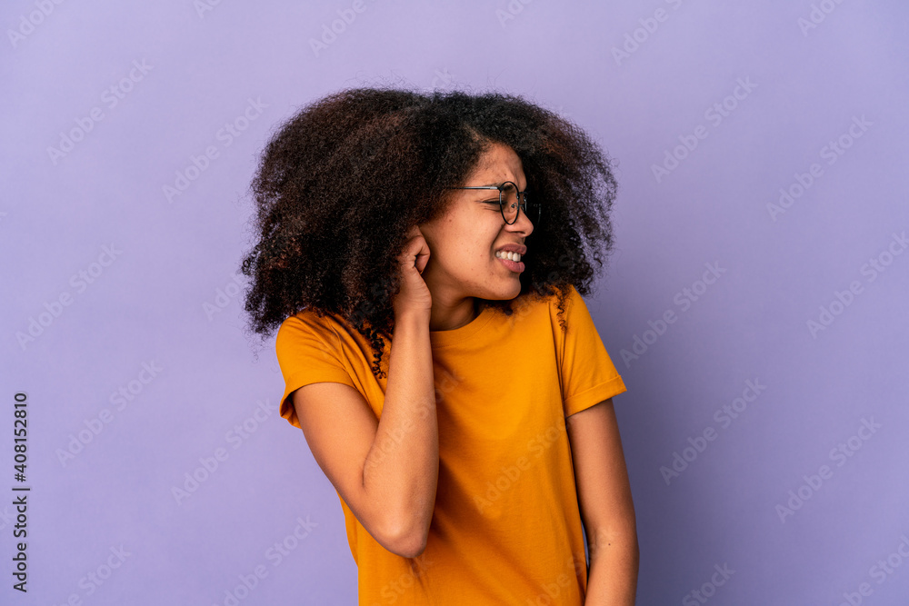 Young african american curly woman isolated on purple background covering ears with hands. Young african american curly woman isolated on purple background covering ears with hands.