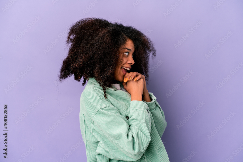 Young african american curly woman isolated on purple background praying for luck, amazed and opening mouth looking to front. Young african american curly woman isolated on purple background praying for luck, amazed and opening mouth looking to front.