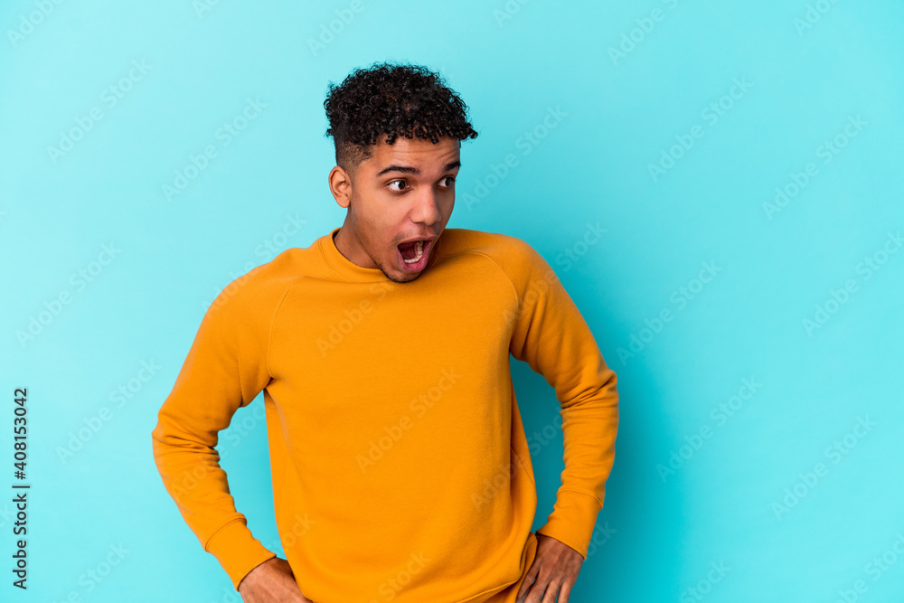 Young african american curly man isolated on blue being shocked because of something she has seen. Young african american curly man isolated on blue being shocked because of something she has seen.