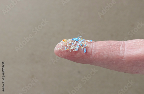 Close up side shot of microplastics on a human finger. Creative concept of water pollution and global warming. Climate change idea. A bunch of plastic rubbish that cannot be recycled. photo