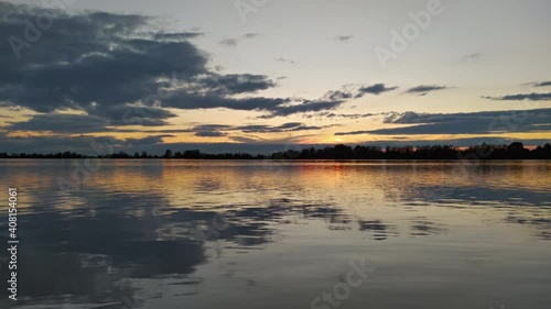 Evening sun moving in clouds with reflection in calm lake photo