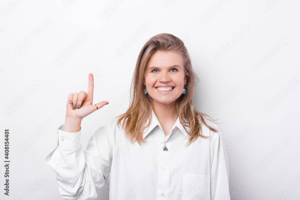 Portrait of smiling young woman pointing up over white background. Portrait of smiling young woman pointing up over white background.