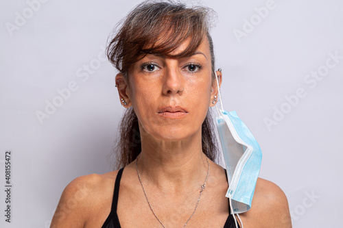 mulher usando máscara de proteção contra coronavírus, pendurada na orelha, mostrando uma maneira incorreta de se vestir photo
