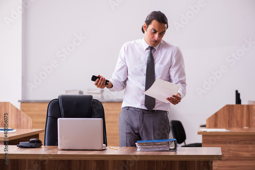 Young male employee stapling paper in the office