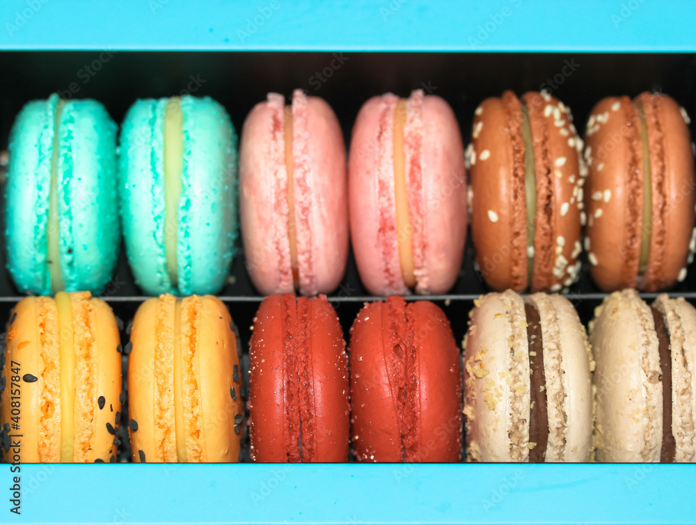 Pile of sweet colourful macaroons in blue gift box, French delicious dessert, Flat lay, top view. Pile of sweet colourful macaroons in blue gift box, French delicious dessert, Flat lay, top view.