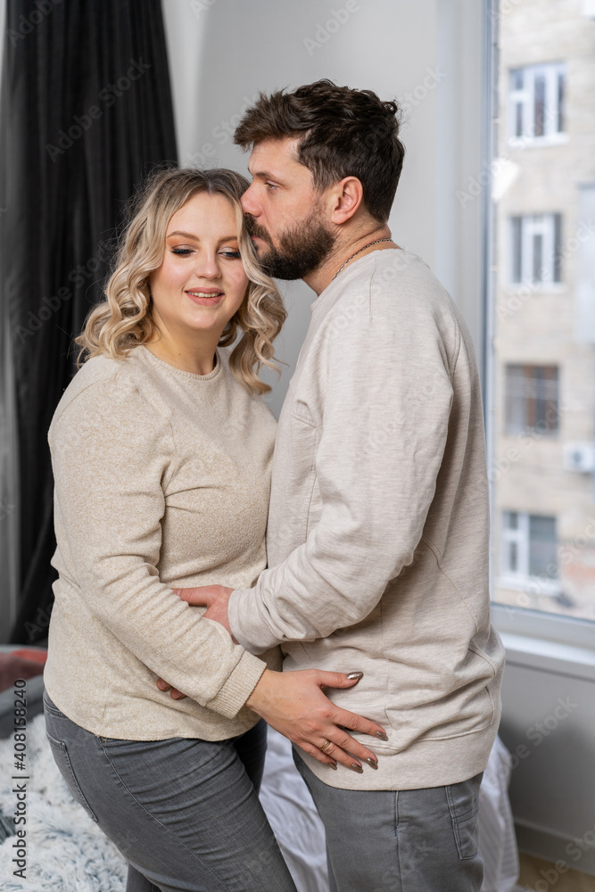 Happy family concept. Husband hug belly pregnant wife standing indoor living room near sofa Happy family concept. Husband hug belly pregnant wife standing indoor living room near sofa