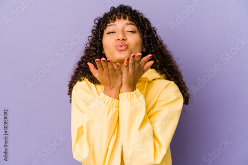 Young african american afro woman isolated folding lips and holding palms to send air kiss. © Asier