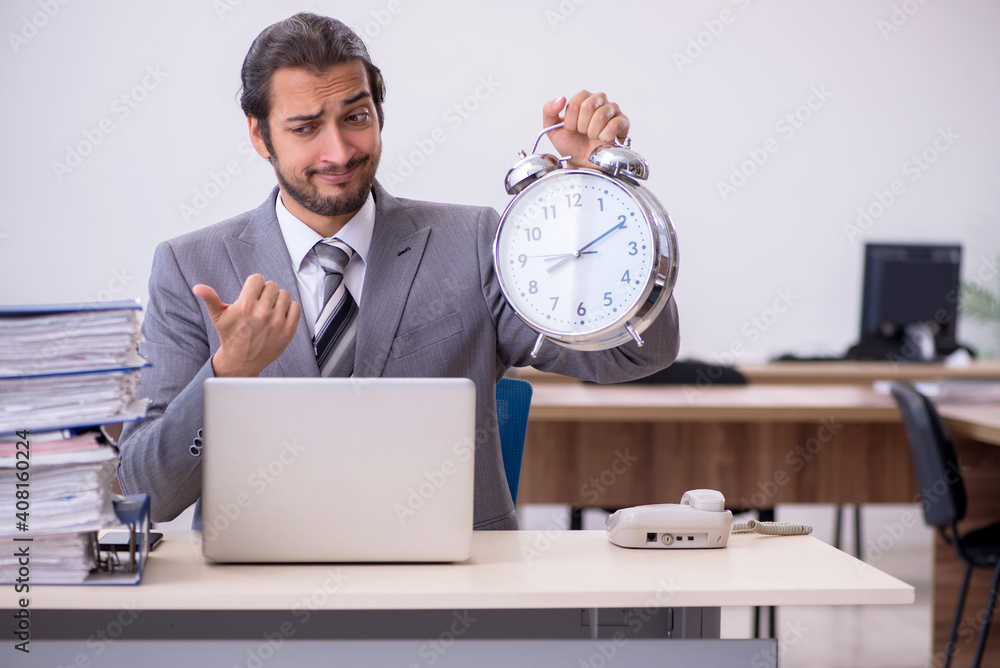 Young male employee in time management concept Young male employee in time management concept