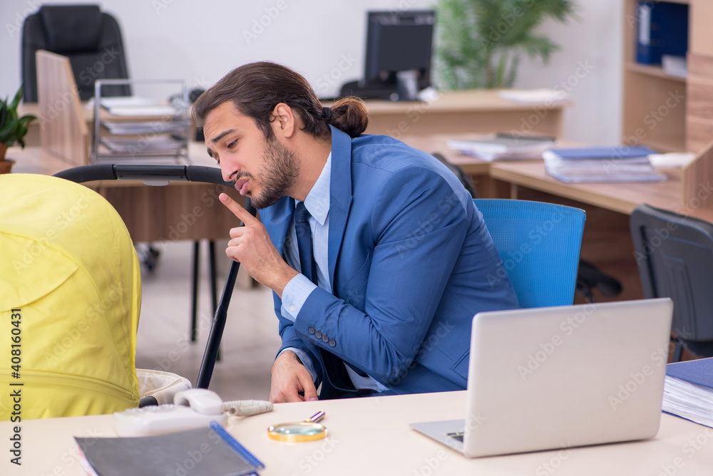 Young male employee looking after new born at workplace Young male employee looking after new born at workplace