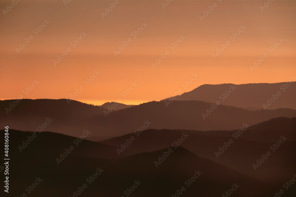 Beautiful landscape with silhouettes of mountain ranges at sunrise.