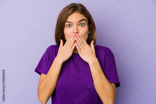 Young skinny caucasian girl teenager on purple background shocked, covering mouth with hands, anxious to discover something new.