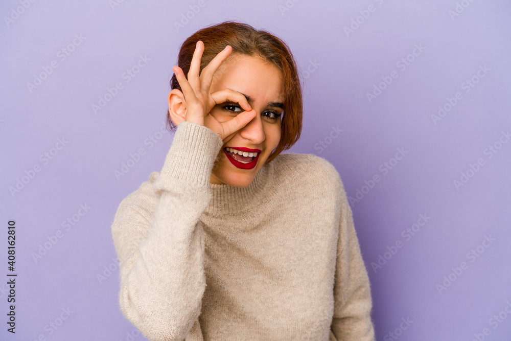 Young arab mixed race woman excited keeping ok gesture on eye.
