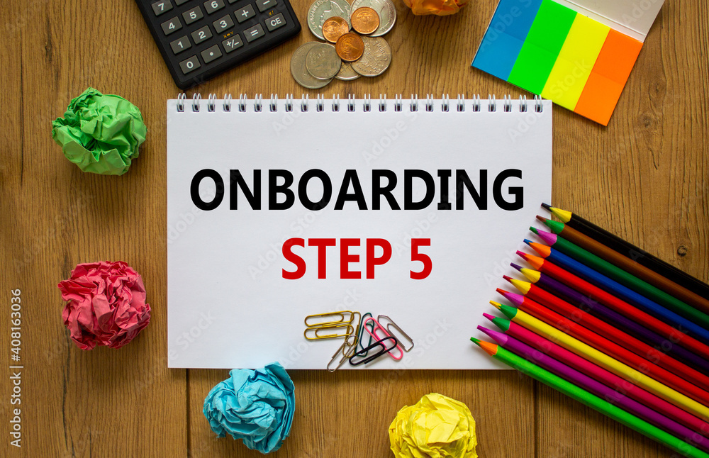 Onboarding symbol. White note with a word 'onboarding step 5' on beautiful wooden table, colored paper, colored pencils, paper clips, coins and calculator. Business and onboarding step 5 concept.